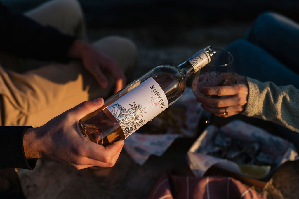 A couple enjoying a bottle of Bunkers wine at the beach 